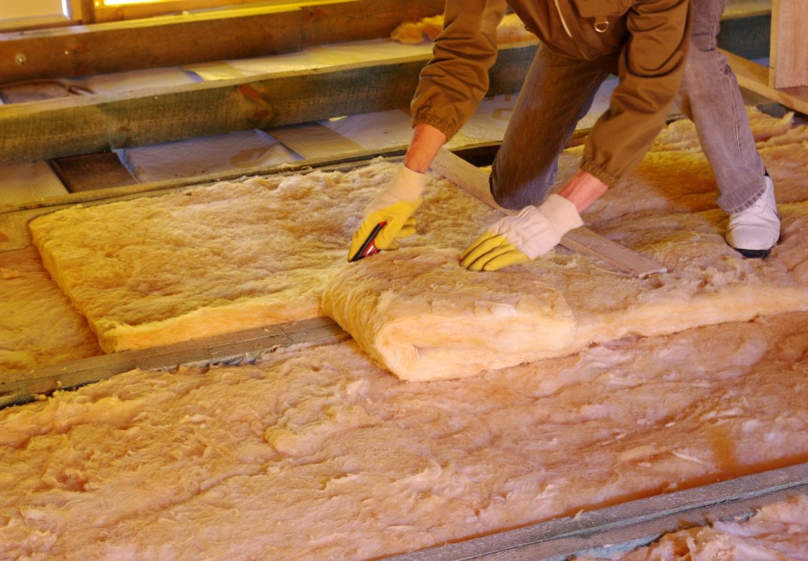 construction worker laying insulation in the roof of a house