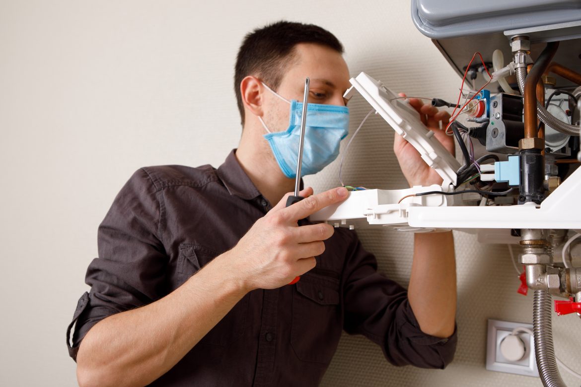 a man repairing a boiler with a facemask on