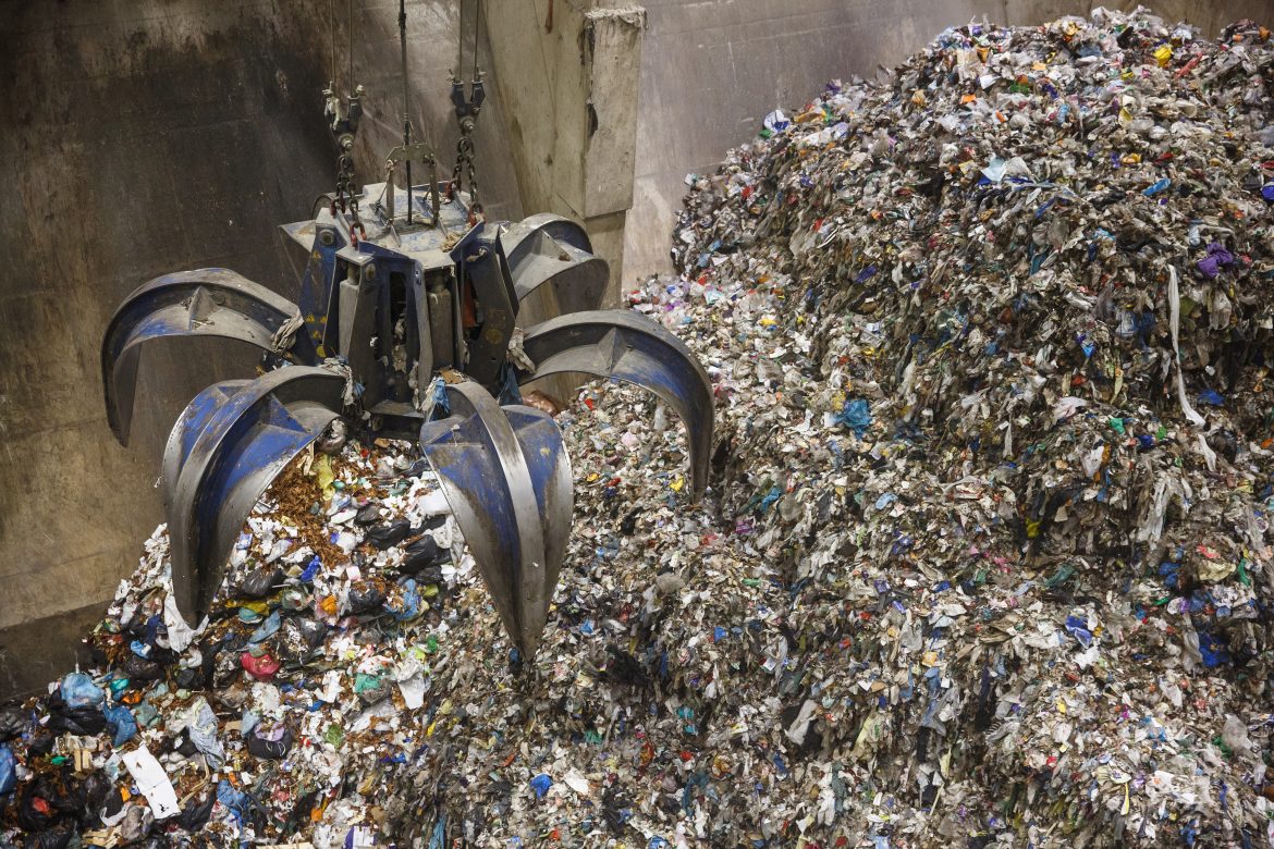 A mechanical claw grabbing waste in a waste plant